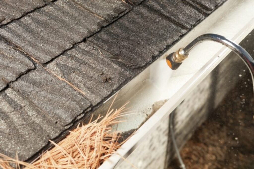 Technician pressure washing gutters in Northern Virginia to prevent water damage